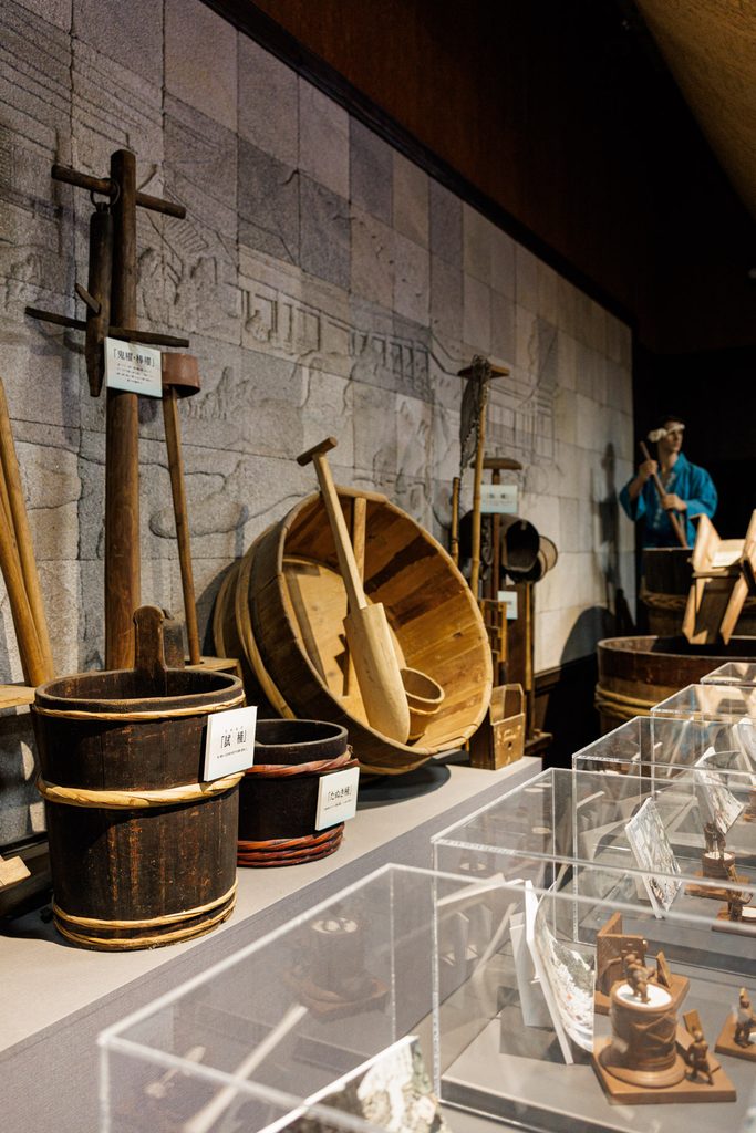 Antique wooden brewing tools and tasting buckets displayed at the free sake museum at Matsuo Taisha
