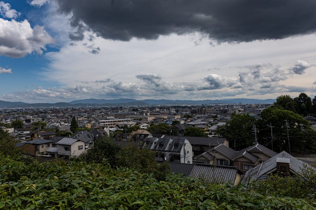View over Kyoto rooftops and distant mountains from the grounds of Suzumushi-dera Temple