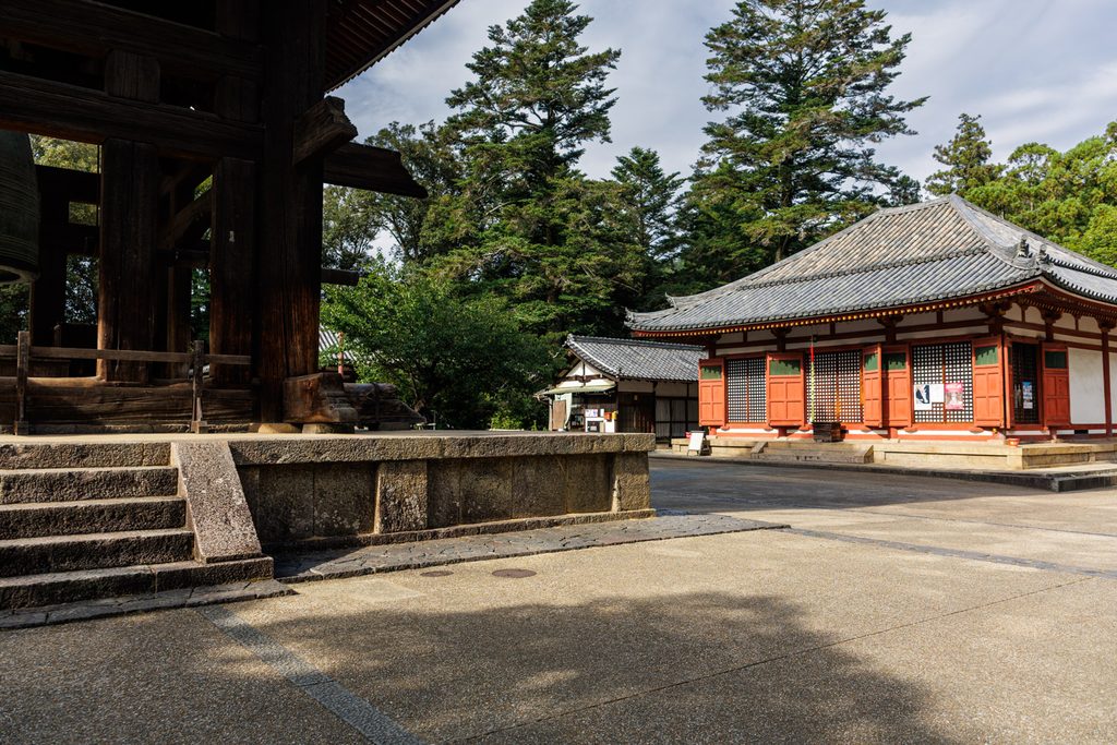 Todaiji bell tower in the foreground with the small temple office and the red Nenbutsudo hall behind it