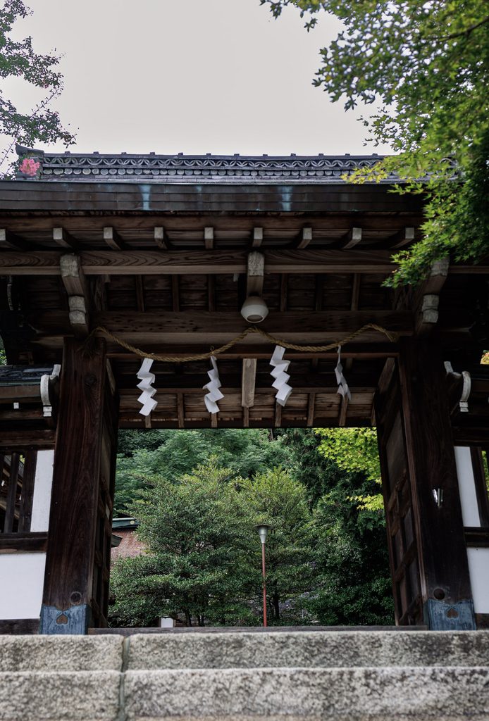 The wooden gate of Tsukiyomi Shrine in Kyoto, hung with a shimenawa rope and white paper streamers