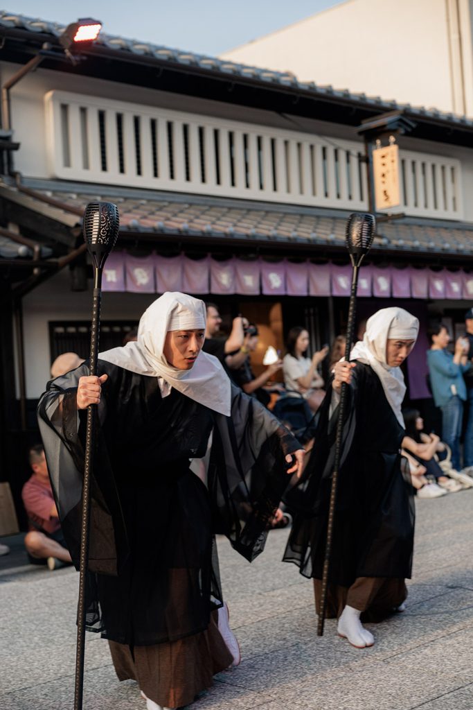 Two performers dressed as warrior monks carrying torch staffs in a Kyoto yokai parade