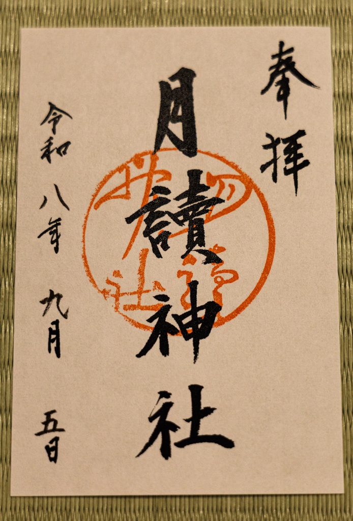 The goshuin of Tsukiyomi Shrine in Kyoto, black brush calligraphy over a round vermilion seal